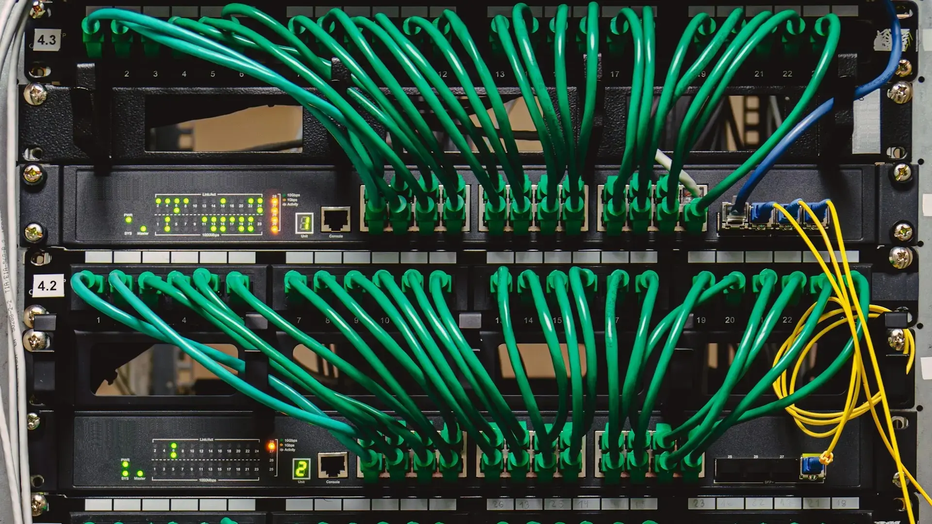 network switches in a rack with neatly bundled green patch cables