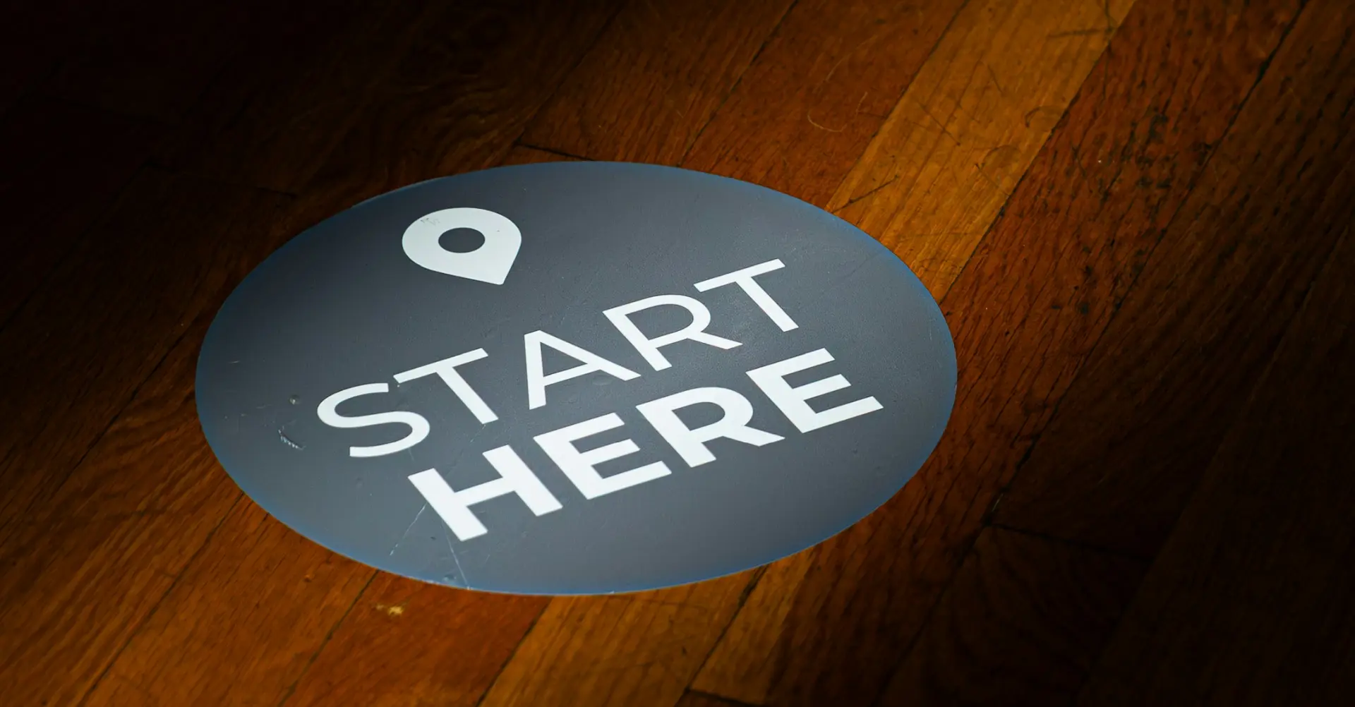 a round floor sticker with start here text